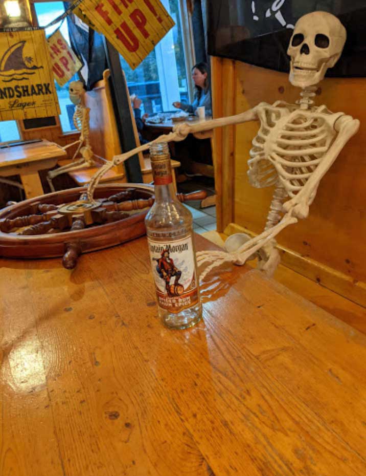 skeleton at table with bottle w