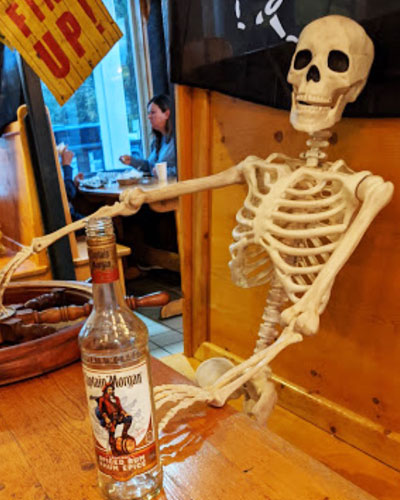 Skeleton with bottle of rum at table